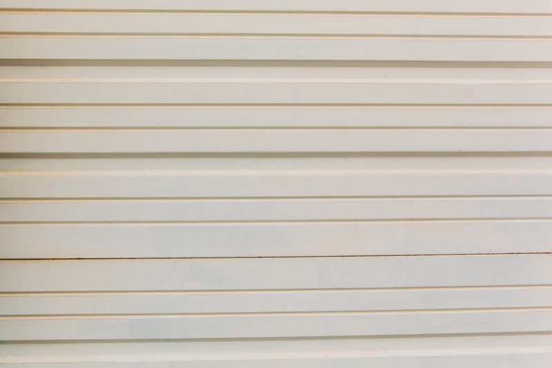 Close up of new garage siding that was recently installed. It is beige and metal.